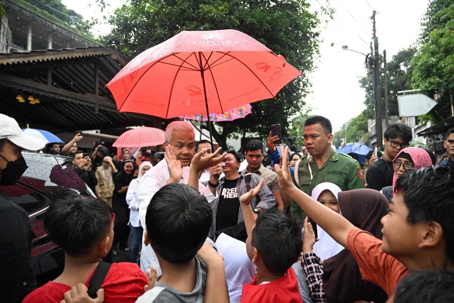 Presidential candidate and former Central Java governor Ganjar Pranowo (L) high fives children after casting his ballot in Indonesia's presidential and legislative elections at a polling station in Semarang, Central Java. - AFP PIC