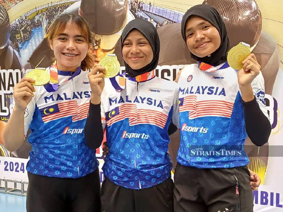 Kedah’s Izzah Izzati Asri (left), Nabilah Asri (centre) and Fitrah Shaari with their team sprint gold medals in Nilai today. 