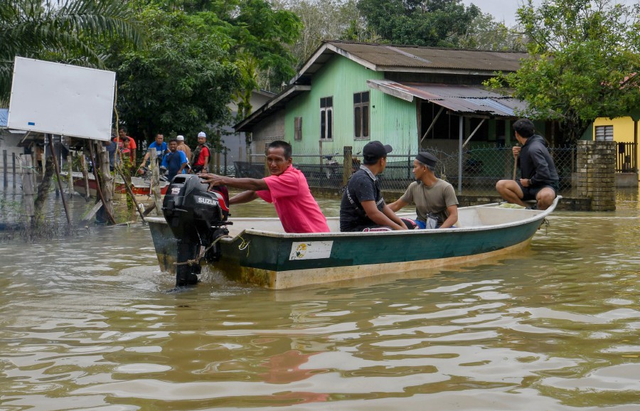 Residents of Kampung Serongga using a boat to relocate to Sekolah Kebangsaan Sri Kiambang relief centre following the floods. - BERNAMA PIC
