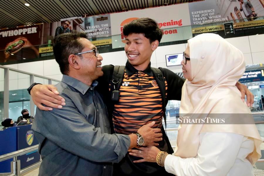 Azeem Fahmi (centre) is embraced by his parents Mohd Fahmi Tajuid and Norazah Ibrahim, upon arriving at Kuala Lumpur International Airport (KLIA), in Sepang on August 10, 2022. - NSTP/AIZUDDIN SAAD