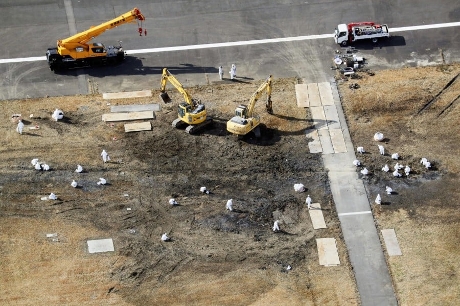 An aerial view shows officials working at the site after removed big wreckage of burnt Japan Airlines' (JAL) Airbus A350 plane after a collision with a Japan Coast Guard aircraft next to it's runway at Haneda international airport in Tokyo. - REUTERS PIC