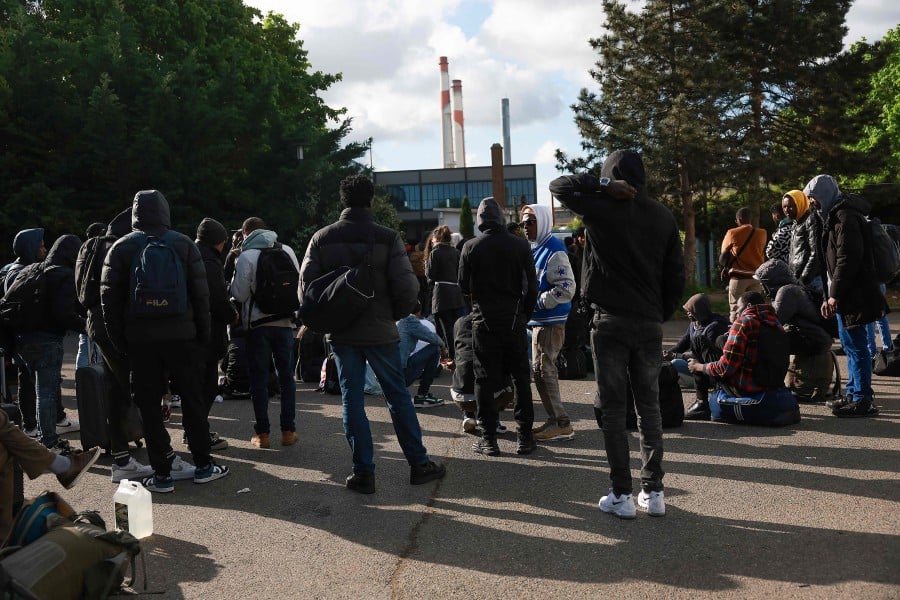 Migrants wait with their belongings to be registered by associations members to get to another location, during the evacuation of France's biggest squat, which has housed up to 450 migrants, most of them legal migrants according to associations - in the southern suburbs of Paris in Vitry-sur-Seine. - AFP PIC