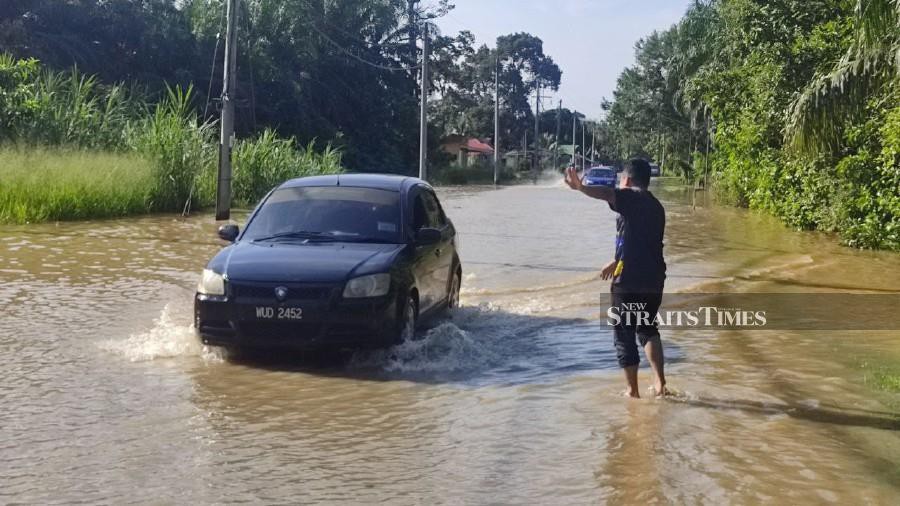 A man helps navigate motorists following the floods in Jalan Slim River towards Felda Besout near Kampung Kuala Slim, on Oct 29. -NSTP/ROSMAN SHAMSUDIN.