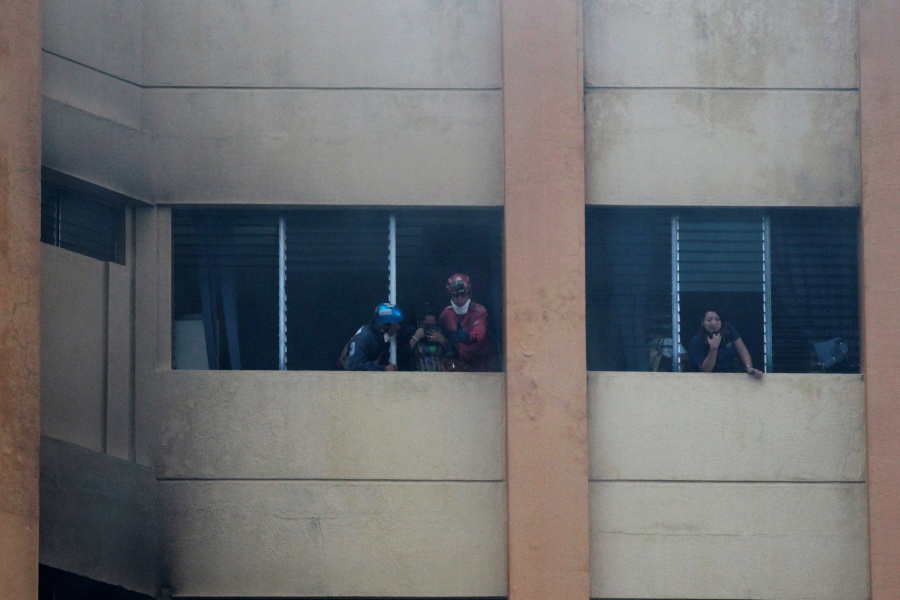 Workers are helped by rescuers at the ministry of treasury building during a blaze in San Salvador, El Salvador. REUTERS