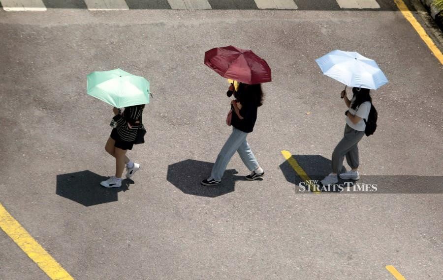  Students using umbrellas to shield themselves from the hot weather at Tunku Abdul Rahman University of Management and Technology. - NSTP/MOHAMAD SHAHRIL BADRI SAALI. 