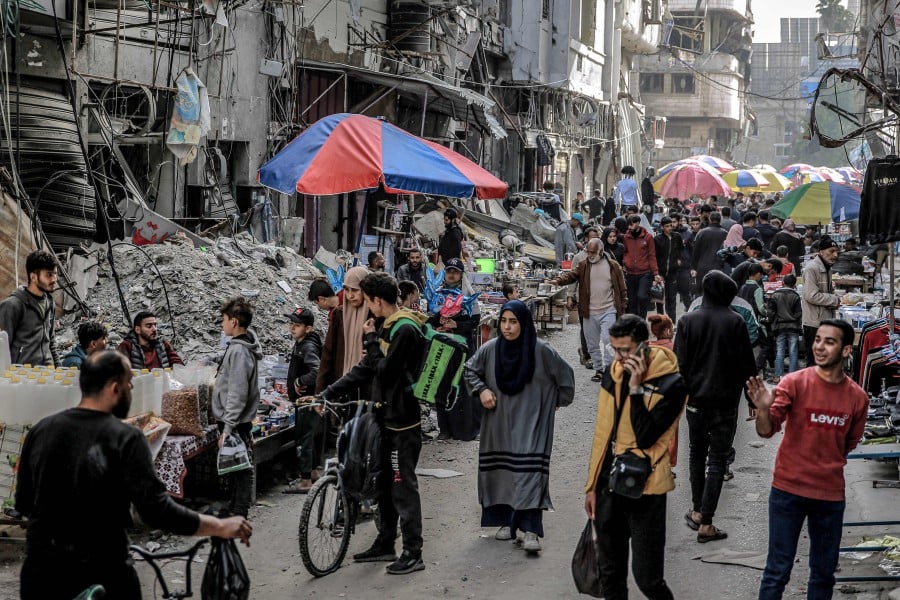 People shop from vendors in an open-air market amidst destruction in Gaza City. - AFP PIC