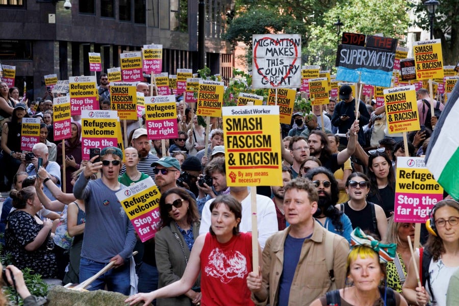 People hold signs at a protest against racism outside Reform UK's headquarters in Westminster, in London. - REUTERS PIC