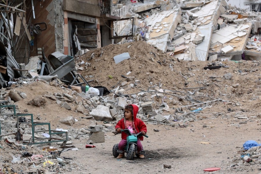 A Palestinian child plays near a building destroyed by earlier Israeli bombardment in Gaza City. - AFP PIC
