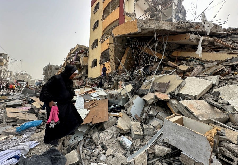 A Palestinian woman searches for her belongings after her apartment was destroyed in an Israeli raid, amid the ongoing conflict between Israel and Hamas, in Nuseirat, in the central Gaza Strip. - AFP PIC