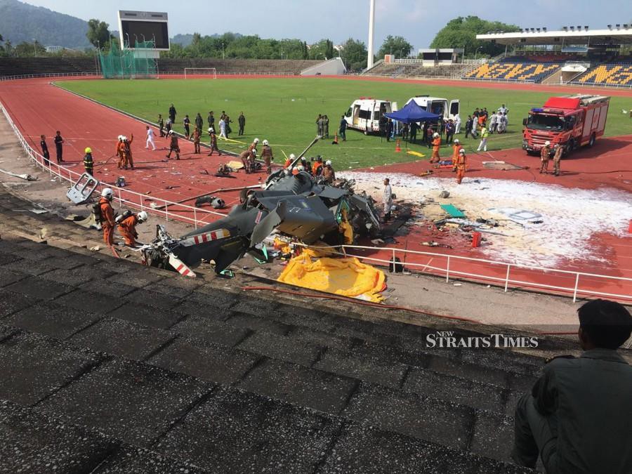 Rescuers are seen attending to the wreckage of RMN’s 503-3 Maritime Operations Helicopter (HOM) on the steps of the Navy Stadium in Lumut. -NSTP/L. MANIMARAN
