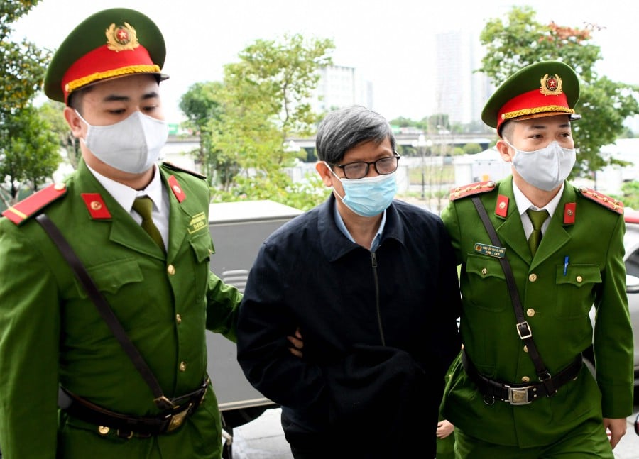 Vietnam's former minister of health Nguyen Thanh Long (C) is led into a court by police for his anti-corruption trial over Covid test kit production bribes in Hanoi on January 3, 2024. - AFP PIC