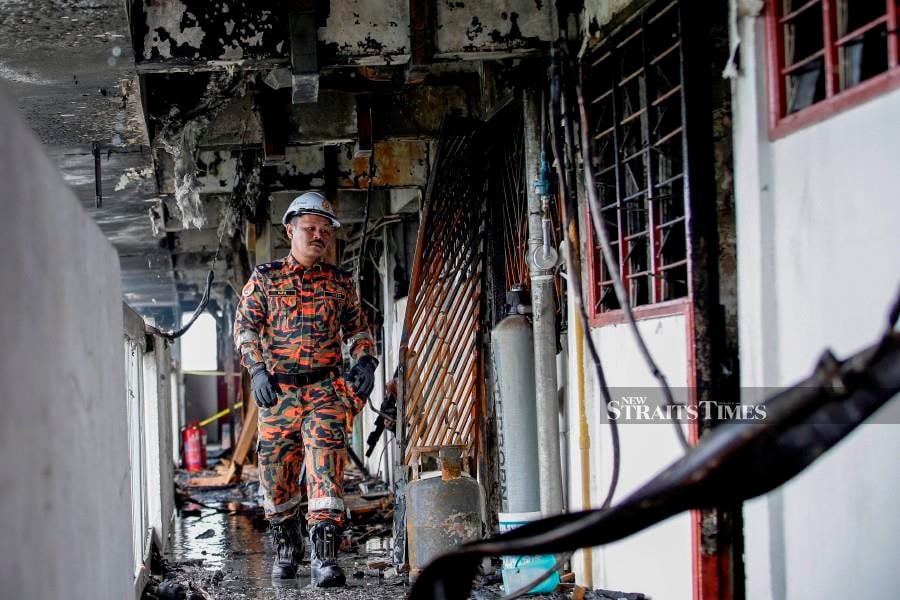 A forensic officer from the Fire and Rescue Dept is seen at the scene following the fire at the Sri Sabah flats in Cheras. -NSTP/AIZUDDIN SAAD