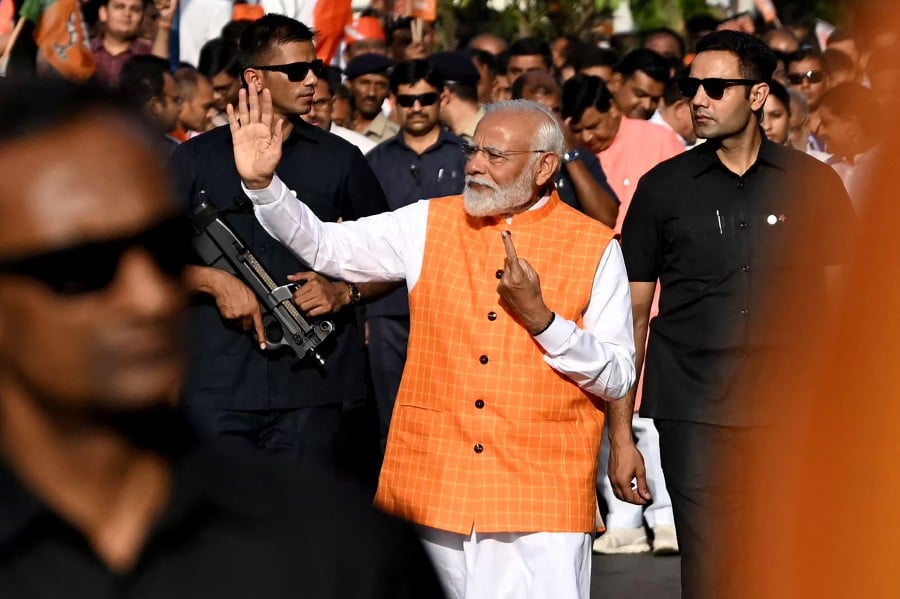 India's Prime Minister Narendra Modi, leader of the ruling Bharatiya Janata Party (BJP) gestures towards the crowd as he leaves after casting his ballot at a polling booth at Ranip, Ahmedabad. - AFP PIC