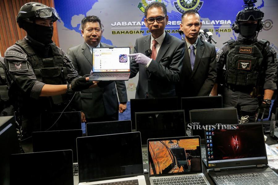 Immigration Department deputy director-general (Operations) Jafri Embok Taha (right) with the department’s special operations and intelligence director Basri Othman show laptops seized from the syndicate, during a press conference in Kuala Lumpur. - NSTP/HAZREEN MOHAMAD