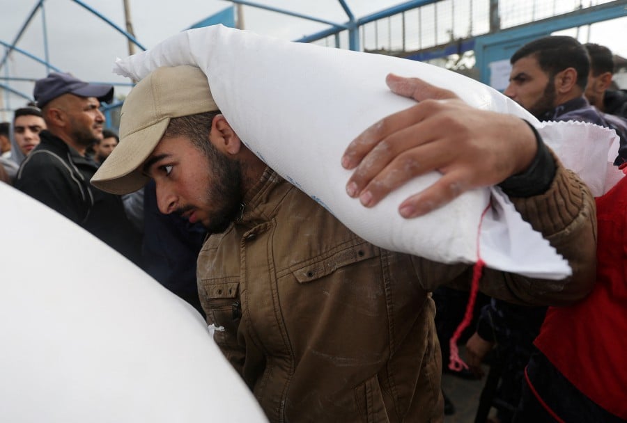 A Palestinian man carries a flour bag distributed by the United Nations Relief and Works Agency (UNRWA) during a temporary truce between Hamas and Israel, in Khan Younis in the southern Gaza Strip Nov 27, 2023. -- Pic: REUTERS