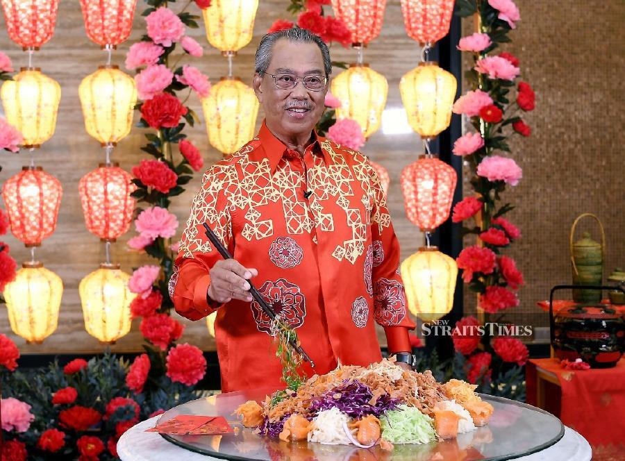 Prime Minister Tan Sri Muhyiddin Yassin tossing the Yee Sang during the Chinese New Year 2021 Open House Celebration which was broadcast virtually. - BERNAMA pic