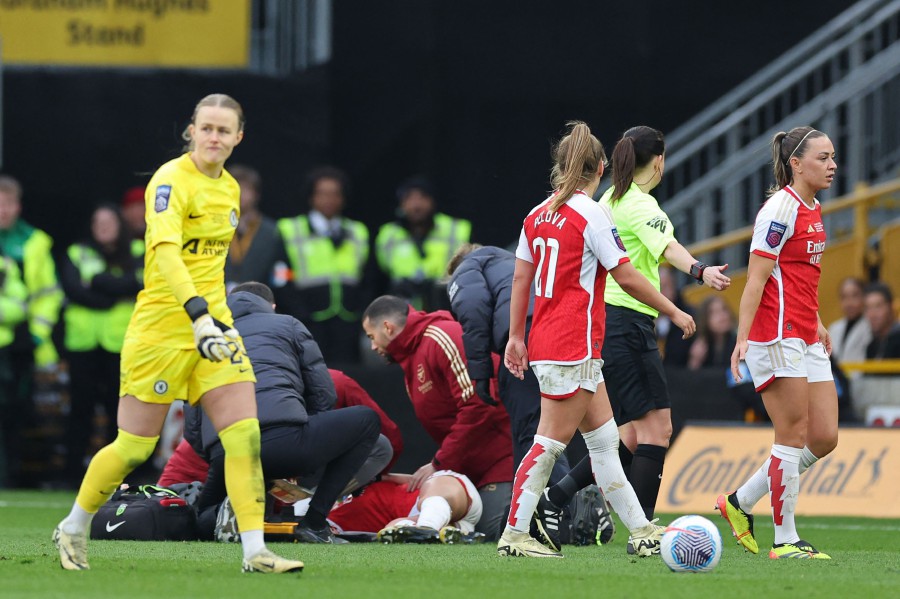 Players start to leave the pitch as Arsenal's Norwegian midfielder #12 Frida Maanum receives medical attention after being taken ill during the English Women's League Cup final football match between Arsenal and Chelsea at Molineux in Wolverhampton, central England. -AFP/Adrian DENNIS
