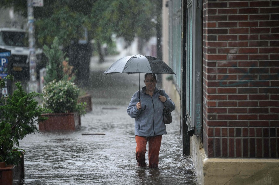 A woman holding an umbrella walks through through floodwater in Brooklyn, New York. -AFP/Ed JONES