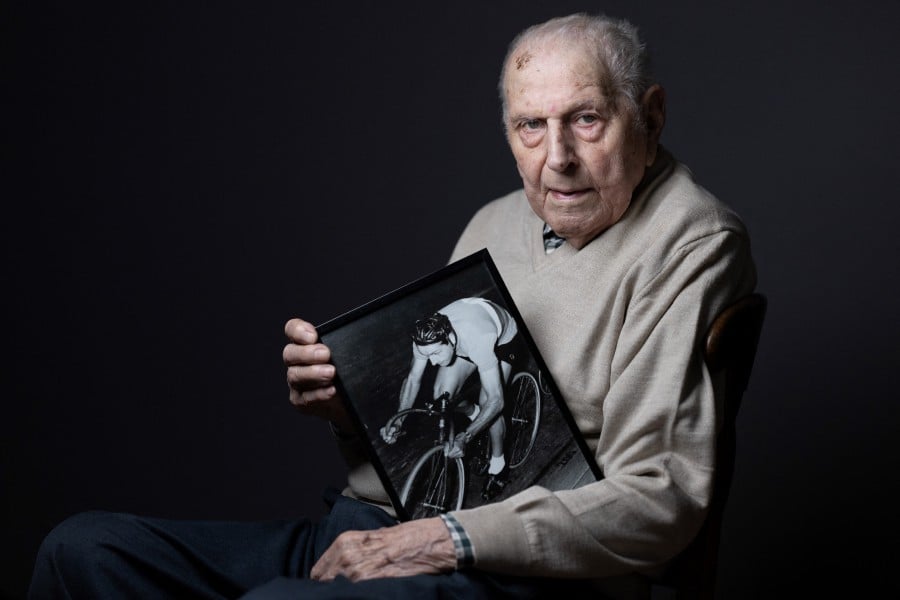 Olympic champion in Men's Team Pursuit in track cycling at the 1948 London Games, Charles Coste, poses with a photo of himself when he was competing during a photo session at home in Bois-Colombes, northwestern of Paris. Charles Coste is the oldest living French Olympic champion. -AFP/JOEL SAGET