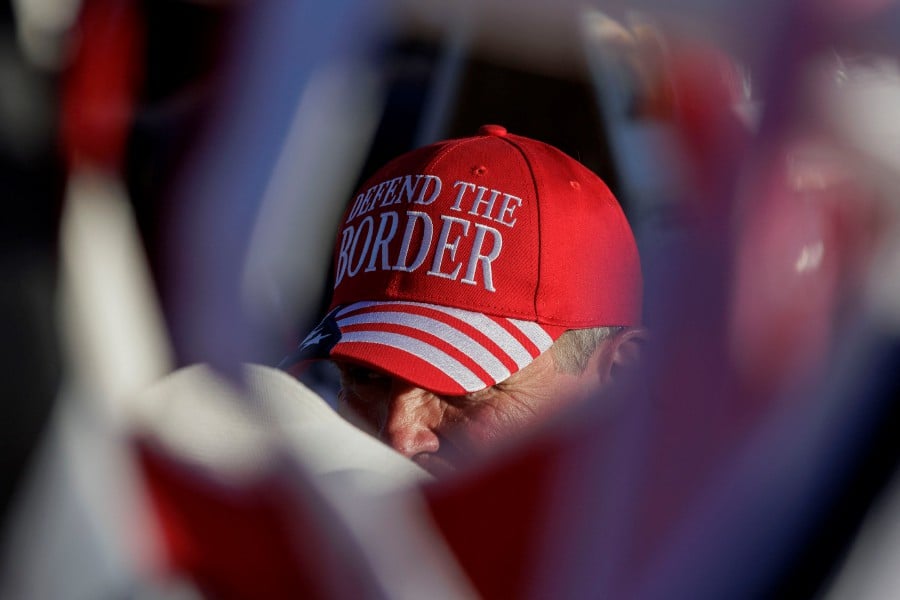 A mab sits with Donald Trump merchandise he sells at the "Take Our Border Back Convoy" rally in Quemado, Texas. (Photo by Michael Gonzalez / GETTY IMAGES NORTH AMERICA / Getty Images via AFP)