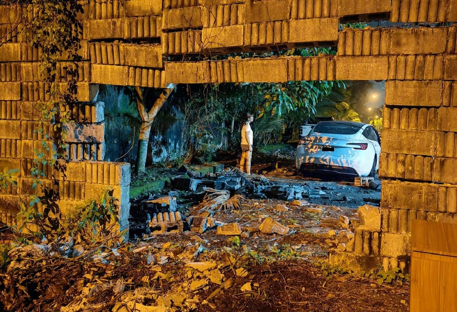 A Tesla crashed through a brick wall, and the driver attributed it to the road being excessively dark. -PIC CREDIT: FACEBOOK/YC SHAUN