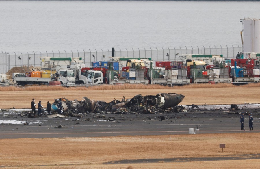 (FILE PHOTO) Officials investigate a burnt Japan Coast Guard aircraft after a collision with Japan Airlines' (JAL) Airbus A350 plane at Haneda International Airport in Tokyo. -REUTERS/Issei Kato
