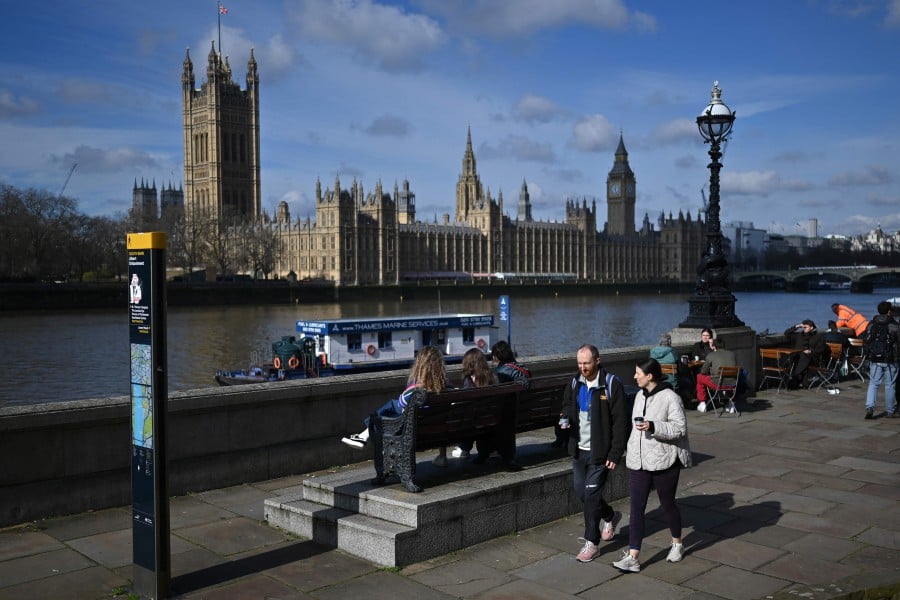 Members of the public walk along the South Bank in the early spring sunshine beside the River Thames, with the Palace of Westminster, home to the Houses of Parliament behind, in London. Britain is in the running to host the 2029 world athletics championships, UK Athletics chief executive. -AFP/Justin TALLIS