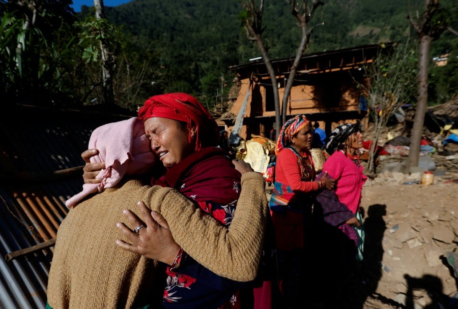 Women cry as they comfort each other while they stand on the debris of a collapsed house that collapsed during an earthquake in Jajarkot, Nepal November 5, 2023. -REUTERS/Navesh Chitrakar