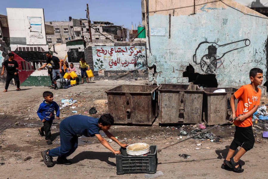 Boys transport a bucket filled with water in Rafah in the southern Gaza Strip on April 5, 2024. -AFP/MOHAMMED ABED