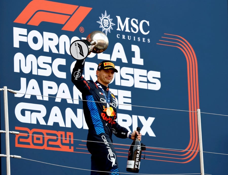 Red Bull's Max Verstappen celebrates with the trophy on the podium after winning the Japanese Grand Prix. -REUTERS/Issei Kato