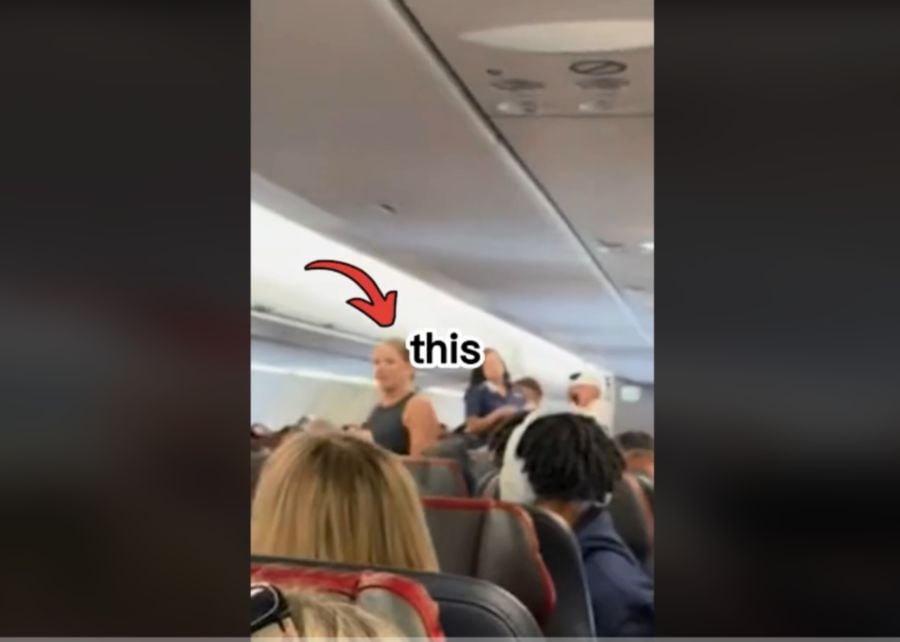 A woman on an American Airlines flight walked down the aisle, warning passengers about a man she claims is "not real". -Image of a screen grab from a TikTok viral video
