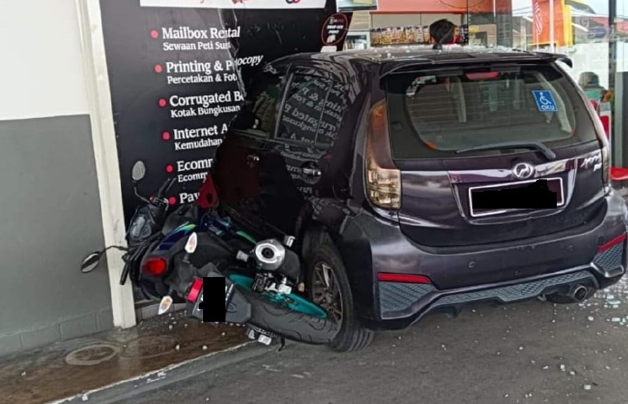 A Swiss national who suffered a leg cramp rammed his car into the glass panel of a petrol station in Taman Canning. -PIC COURTESY OF PDRM