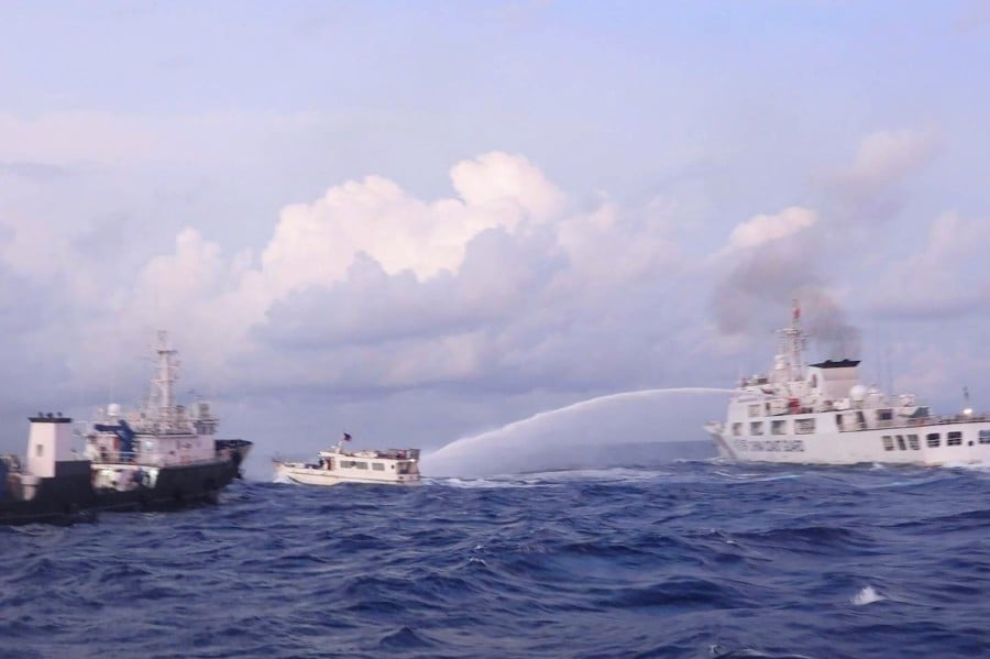 This handout photo taken and released on December 10, 2023 by the Philippine Coast Guard (PCG) shows a China Coast Guard vessel (right) using water cannon against the M/L Kalayaan chartered supply boat (centre) during a mission to deliver provisions at Second Thomas Shoal in disputed waters of the South China Sea. The Philippine Coast Guard also said a Chinese ship "water cannoned" three Philippine vessels involved in the re-supply mission, causing "serious engine damage" to one of the boats. -AFP/Handout/Philippine Coast Guard (PCG)
