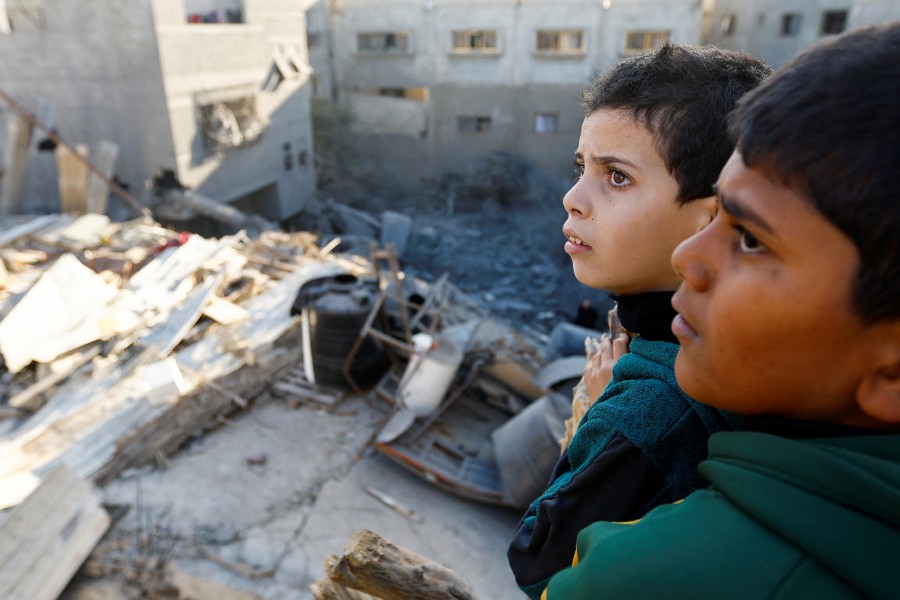 Palestinian children look at the damage at the site of Israeli strikes on houses in Khan Younis in the southern Gaza Strip, December 10, 2023. -REUTERS/Ibraheem Abu Mustafa