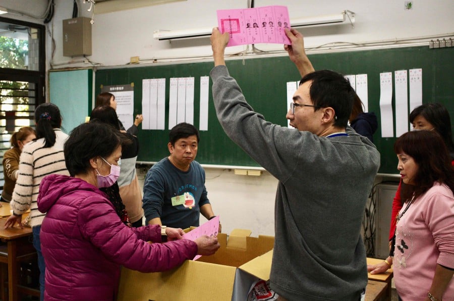 An official of a polling station holds up a ballot slip, as vote counting for the presidential elections commences, at a high school in New Taipei City on January 13, 2024. Vote counting got under way on January 13 in Taiwan's presidential election, held in the shadow of threats from China that choosing the wrong leader could set the stage for war on the self-ruled island. -AFP/Sam Yeh