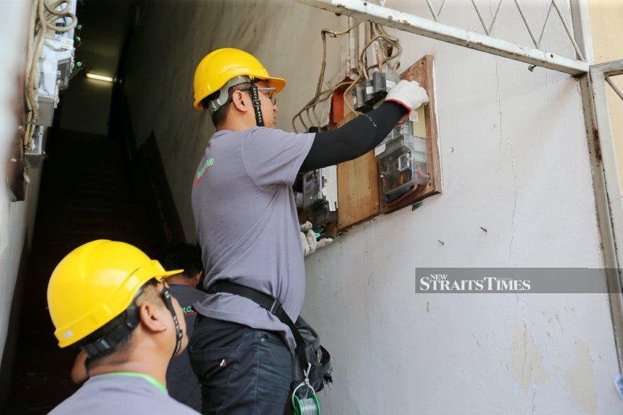 (FILE PHOTO) A technician from Sabah Electricity Sdn Bhd (SESB) examines the electrical box. -NSTP FILE