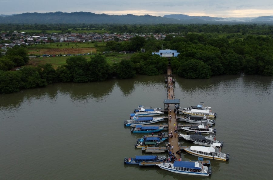 (FILE PHOTO) Aerial view showing migrants getting on boats in the Colombian port town of Turbo, close to the Darien Gap, a jungle shared by Colombia and Panama, before continuing their journey towards the United States in hope of a better life. -AFP/Juan RESTREPO