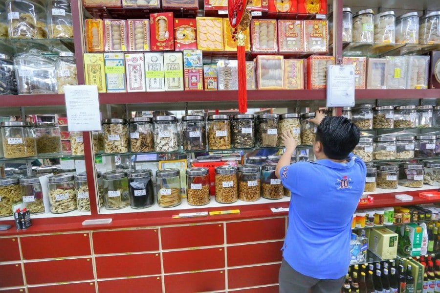 KUALA LUMPUR: A worker at a traditional Chinese medicine and herbal shop arranges containers on the shelf following the government's decision to exempt Traditional and Complementary Medicine (TCM) from the Sales and Service Tax (SST). -NSTP/SAIFULLIZAN TAMADI