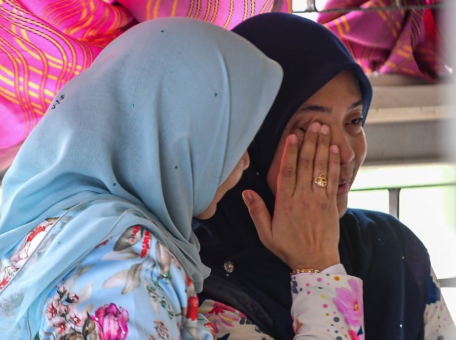 The mother of Nuqman Naufal Shamsul Fadzli (right), the student who was rushed to the hospital after collapsing during a cross-country activity, couldn't hold back her tears at Tuanku Ampuan Najihah Hospital's (HTAN) forensic unit. -BERNAMA PIC