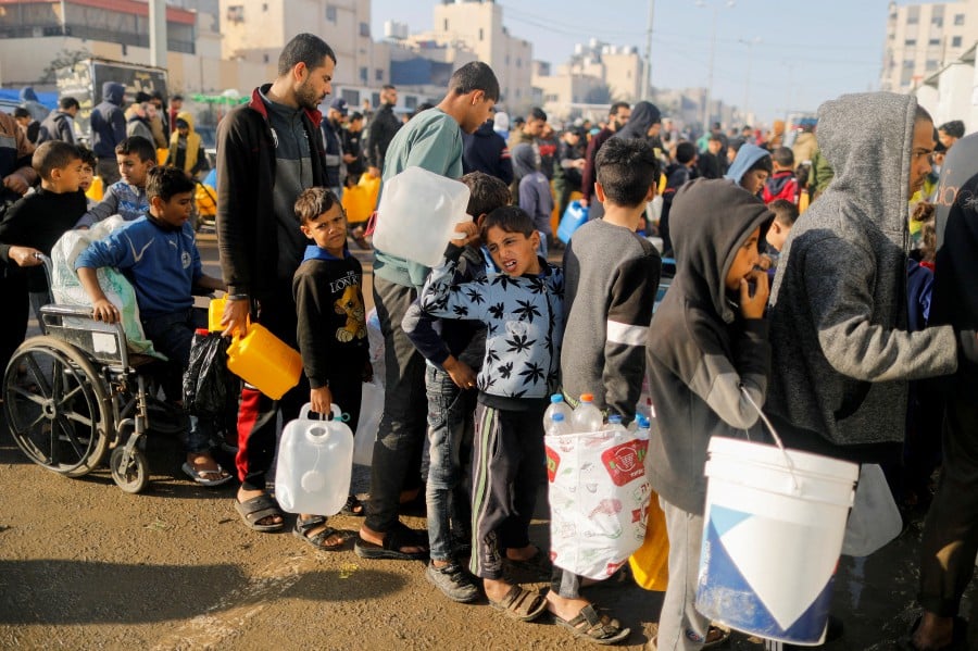 Palestinians queue as they wait to collect drinking water, amid shortages of drinking water in Rafah, in the southern Gaza Strip. -REUTERS/Saleh Salem