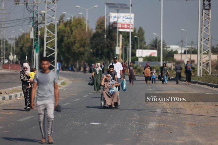 People carrying some of their belongings reach the central Gaza Strip on foot via the Salah al-Din road on their way to the southern part of the Palestinian enclave. -AFP/MOHAMMED ABED