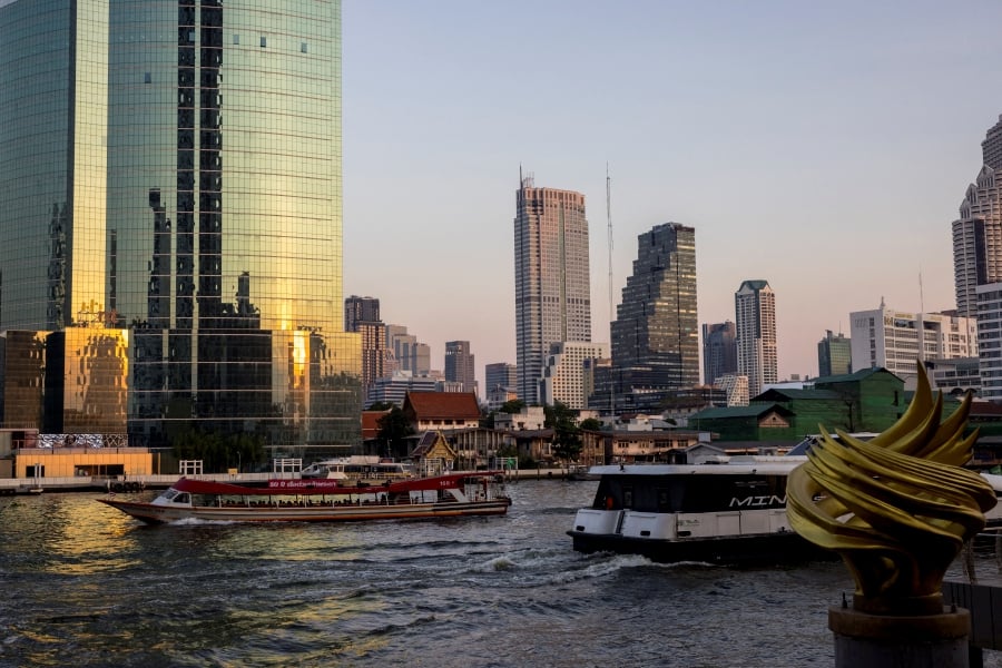 Two boats pass each other on the Chao Phraya River in front of the Bangkok skyline. (Photo by Jack TAYLOR / AFP)