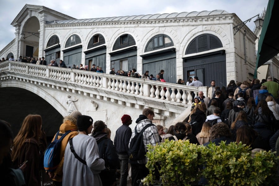 People queue to visit the Rialto Bridge on April 24, 2024 in Venice, on the eve of the start of the official trial of the city's booking system for day-trippers. Venice will begin on April 25, 2024 charging day trippers for entry, a world first aimed at easing pressure on the Italian city drowning under the weight of mass tourism. -AFP/MARCO BERTORELLO