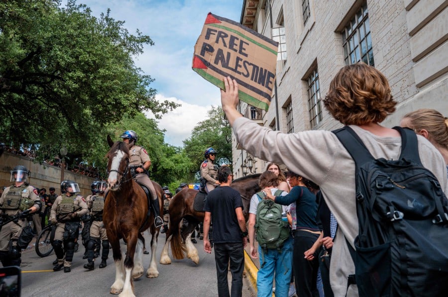 Police keep watch over demonstrators protesting the war in Gaza at the University of Texas at Austin on April 24, 2024 in Austin, Texas. Students walked out of class as protests continue to sweep college campuses around the country. -AFP/Brandon Bell