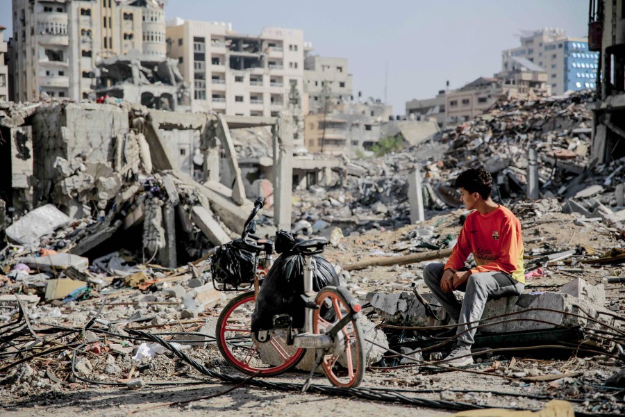 A Palestinian youth sits next to his bicycle amid the rubble of destroyed buildings in Gaza City on the northern Gaza strip following weeks of Israeli bombardment, as a four-day ceasefire took effect on November 24, 2023. The United States (US) President Joe Biden on Friday said "chances are real" to extend the humanitarian pause between Hamas and Israel in the Gaza Strip. -AFP PIC