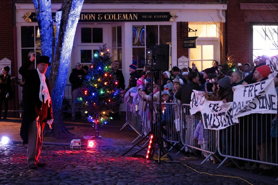 A town crier rings a bell in front of protesters holding "Free Palestine" banners after a Christmas lighting attended by US President Joe Biden on Main Street during his Thanksgiving vacation in Nantucket, Massachusetts. -AFP/Brendan Smialowski