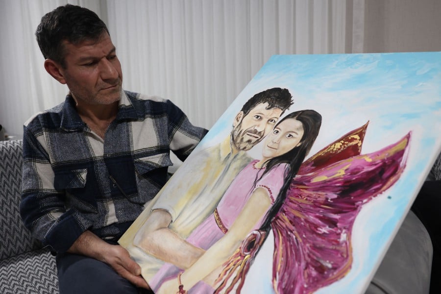 Mesut Hancer holds a painting of his daughter 15-year-old-daughter Irmak, victim of the earthquake that hit Turkey's southeast on February 6, 2023, during an interview, in Ankara on Jan 11, 2024. -AFP/Adem ALTAN