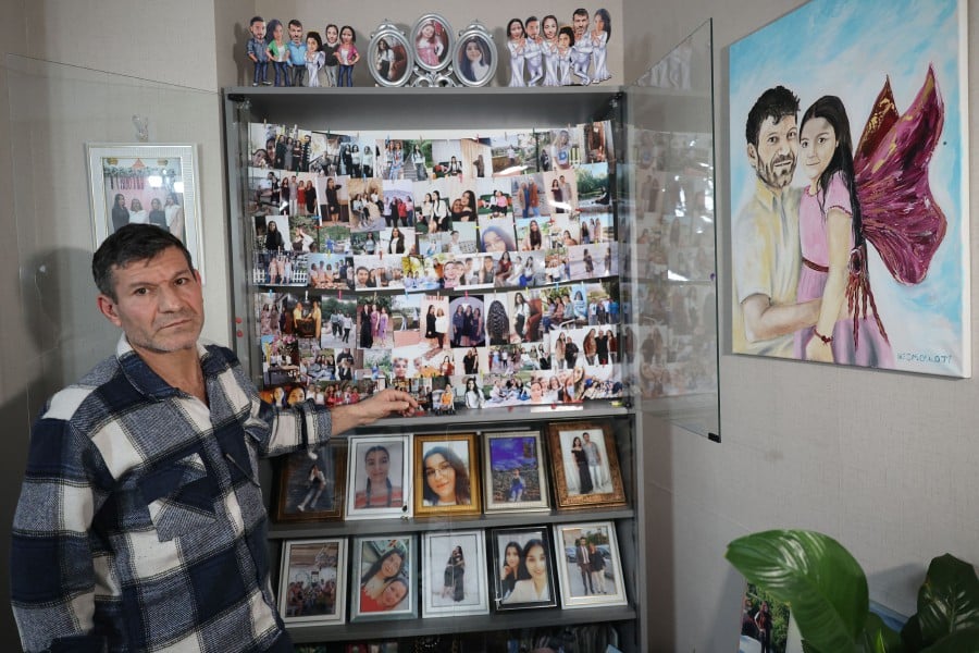 Mesut Hancer, stands infront of photographs of his 15-year-old-daughter Irmak, victim of the earthquake that hit Turkey's southeast on February 6, 2023, during an interview in Ankara on Jan 11, 2024. -AFP/Adem ALTAN