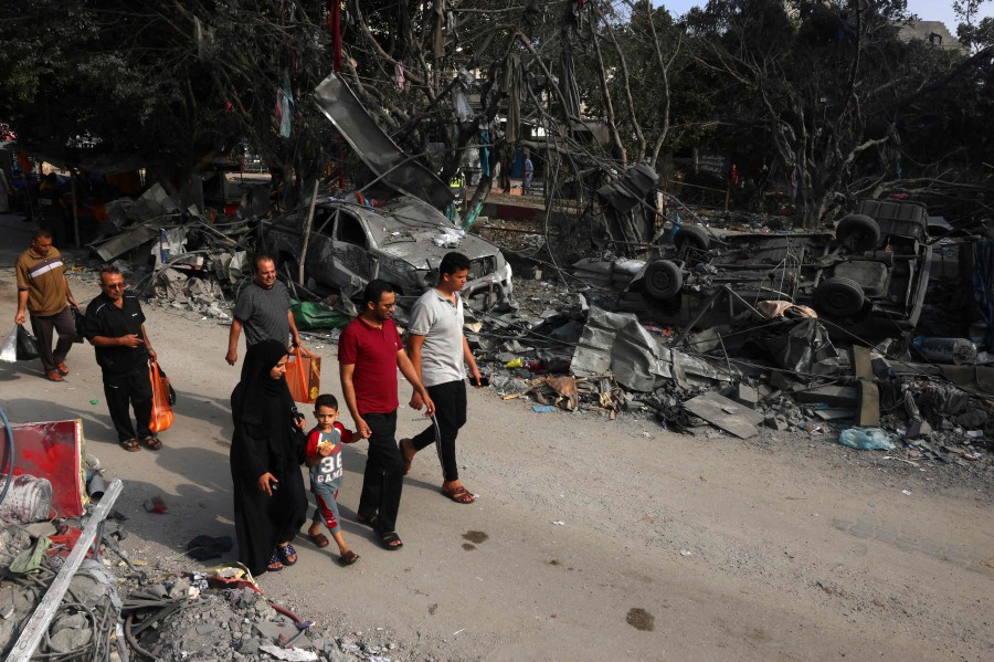 People walk past wrecked cars in the aftermath of Israeli bombing in Rafah in the southern Gaza Strip on October 28, 2023. -AFP/SAID KHATIB