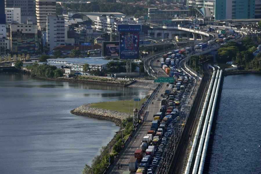 (FILE PHOTO) Vehicles form a long queue to enter Woodlands checkpoint in Singapore from across the causeway of the southern Malaysian state of Johor. -AFP/Catherine LAI
